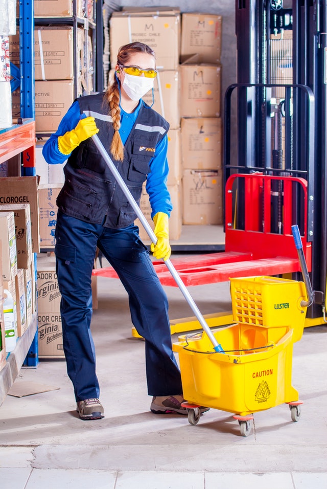 Woman With a Mop and Bucket in a Warehouse