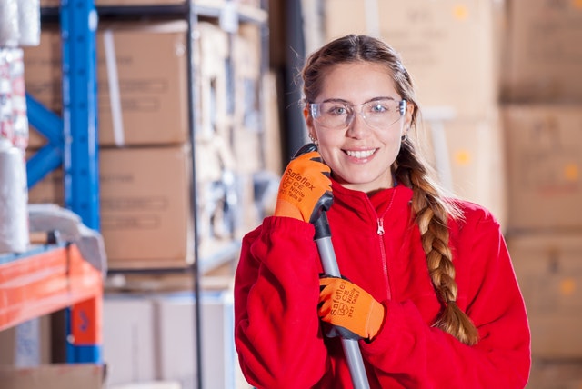 Michigan Employment Services Woman Working in Warehouse Holding Broom